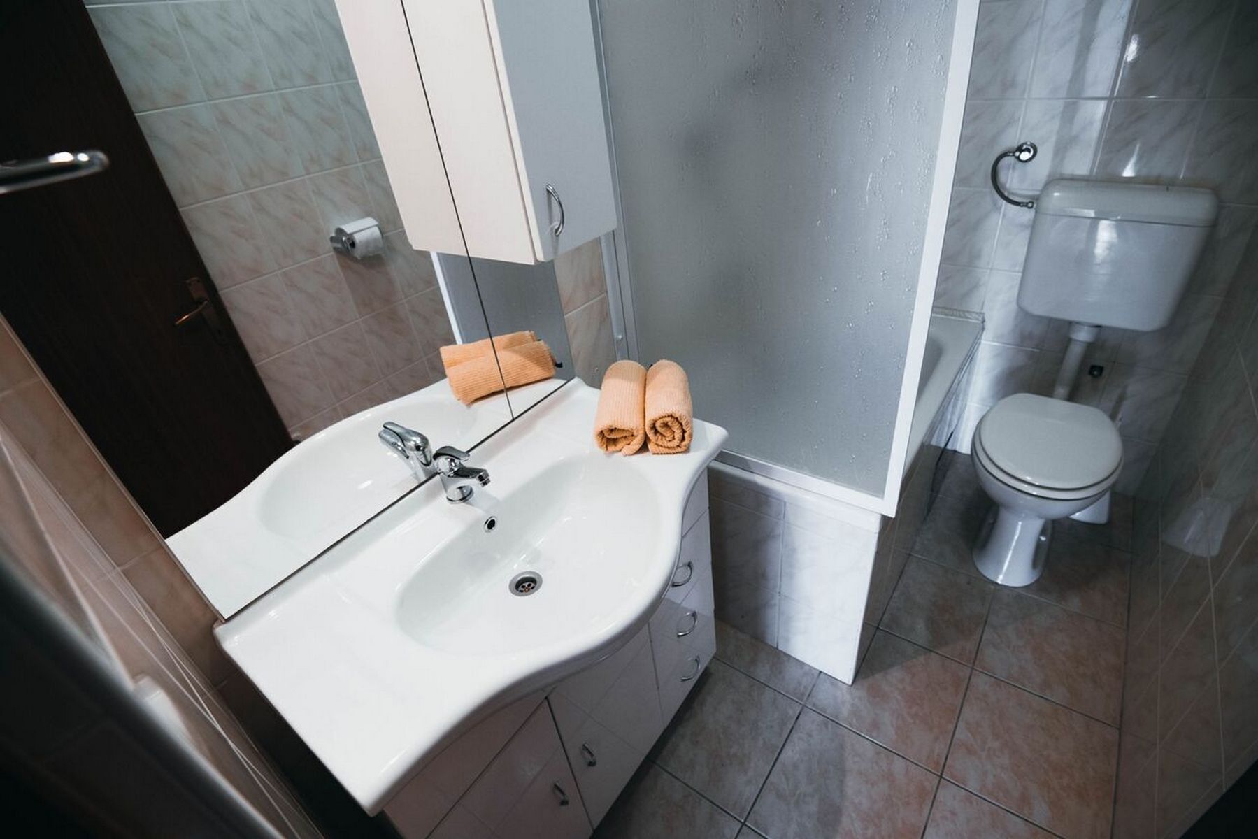 A bathroom with a white sink, a toilet, and a shower area.