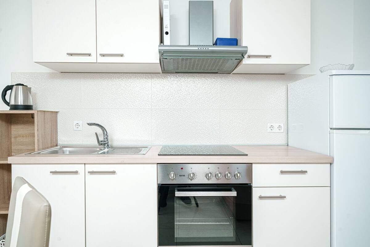 A modern kitchen with white cabinets, a stainless steel range, an oven, and a sink.