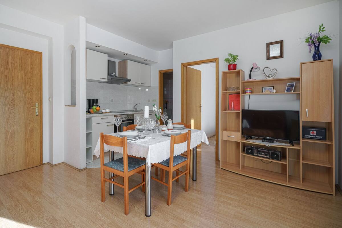 A compact living space with a dining area, kitchen, and entertainment unit.