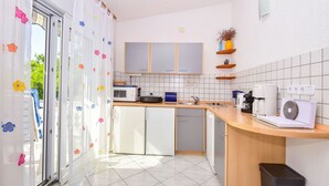A modern kitchen with white cabinets, a microwave, a coffee maker, and a trash bin. - Apartments Rote Rosen (Sabunike)