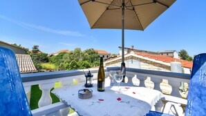 A balcony with a table set for two, a bottle of wine, a glass, and a candle. - Apartments Rote Rosen (Sabunike)