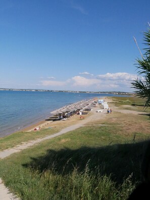 Une plage avec des parasols et un sentier qui mène à l’eau.