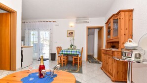 A dining area with a round wooden table, chairs, a small chandelier, and a wooden cabinet with glass doors. - Apartments Rote Rosen (Sabunike)