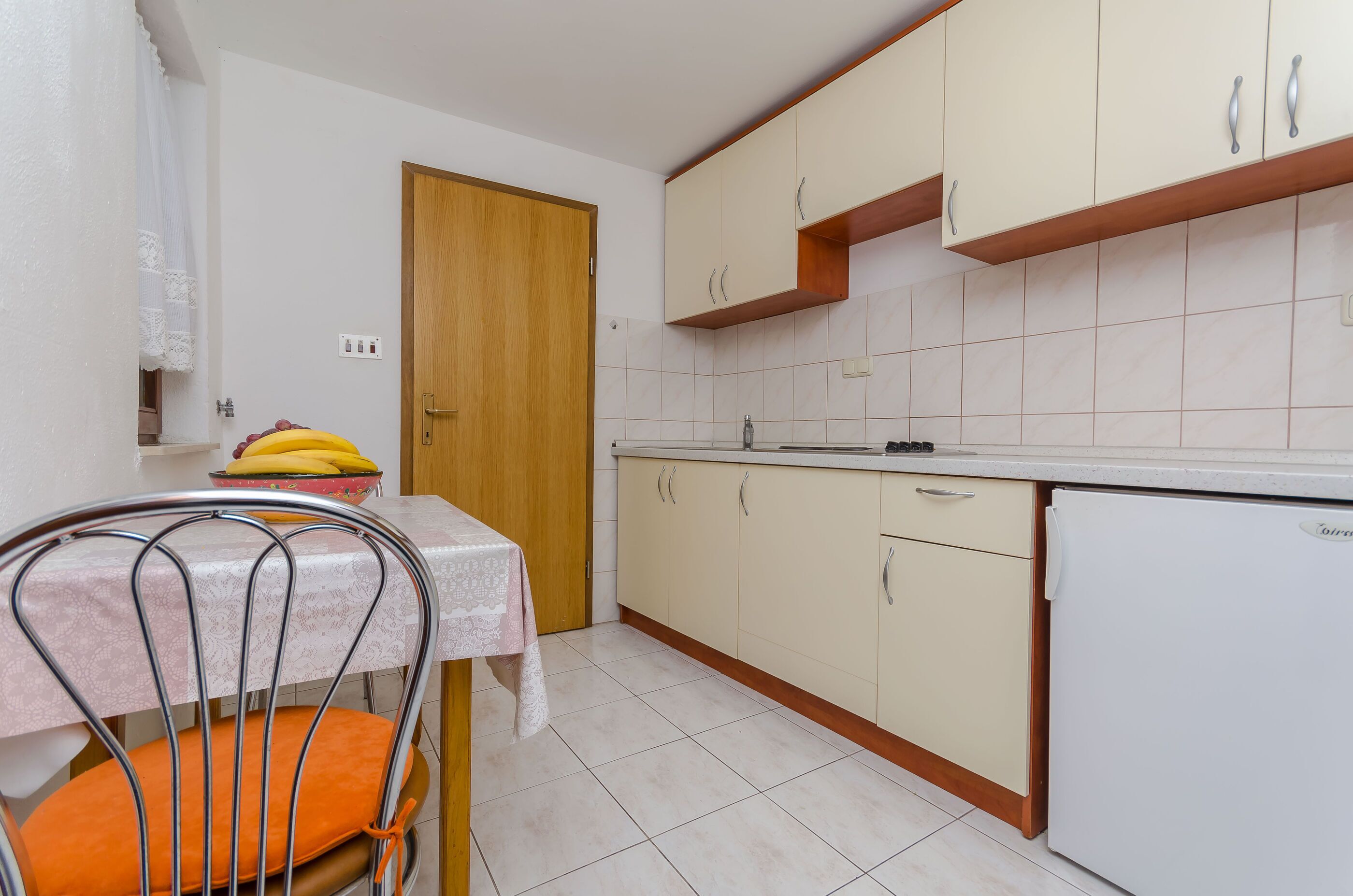 A small kitchen with a table, chairs, and a refrigerator.