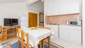 A compact living space with a dining area, kitchenette, and a television.
