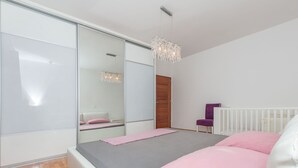 A modern bedroom with a large bed, a sliding glass door, a white radiator, and a purple chair. - Apartment Mario (Strozanac)