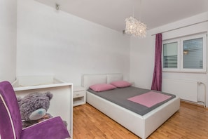 A bedroom with a bed, a nightstand, a dresser, a teddy bear, and a hanging light fixture.