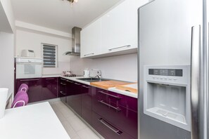 A modern kitchen with a built-in water dispenser, stainless steel appliances, and purple cabinetry.