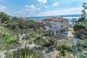 A multi-story building with a balcony, surrounded by vegetation and a view of the sea. - Apartments Clarus Mare (Dugi Rat)