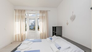 Une chambre d’hôtel avec un lit, deux jeux de serviettes, une armoire et une vue sur l’extérieur, visible à travers une porte.