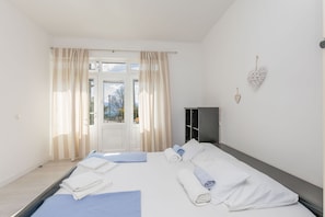 A hotel room with a bed, towels, a wardrobe, and a view through a window. - Apartments Clarus Mare (Dugi Rat)