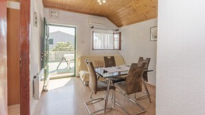 A dining area with a wooden ceiling, a glass table, and four chairs. - Apartments Romic (Jadrija)
