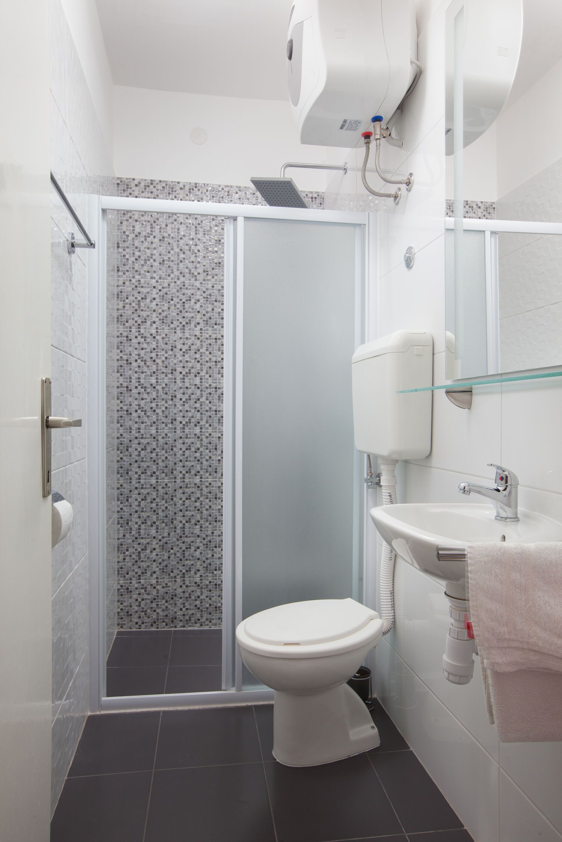 Une salle de bain équipée d’une douche, de toilettes, d’un lavabo et d’une étagère en verre.
