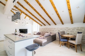 Une cuisine moderne dotée d’un îlot central, de poutres en bois et de luminaires suspendus.