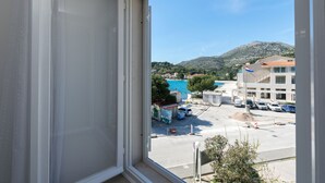 Blick aus einem Fenster auf einen Parkplatz mit Gebäuden und einem Berg im Hintergrund.