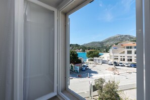 A view from a window overlooking a parking lot with buildings and a mountain in the background.