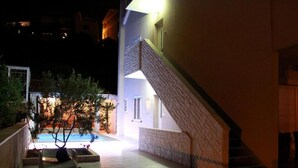 A nighttime view of a building with a pool, a staircase, and a bench. - Apartment Golden Sunset (Sibenik)