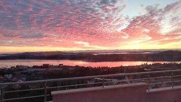 Une vue panoramique d’un lac au coucher du soleil, avec un ciel dégagé et des montagnes lointaines.