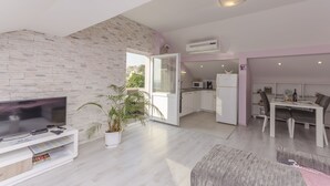 A modern apartment with a flat-screen TV, a dining area, and a kitchen. - Apartment Golden Sunset (Sibenik)