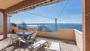 Ein Balkon mit Tisch und Stühlen, der einen malerischen Blick auf das Meer und die Berge bietet.