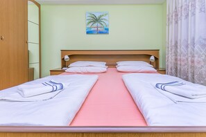 Ein Doppelbett mit rosa Bettwäsche, ein Holzkopfstück und ein Palmenbaumgemälde an der Wand.