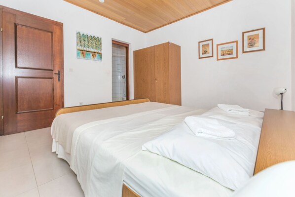 A bedroom with a bed, wooden wardrobe, and a door. - Apartments Mara (Duce)
