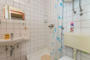 A bathroom with a white sink, a mirror, a shower with a dolphin-patterned shower curtain, and a toilet. - Apartments Mara (Duce)