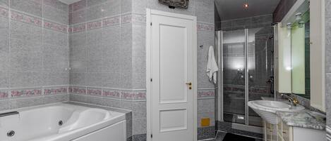 A modern bathroom with a bathtub, a glass-enclosed shower, a vanity with a sink, and a large mirror.