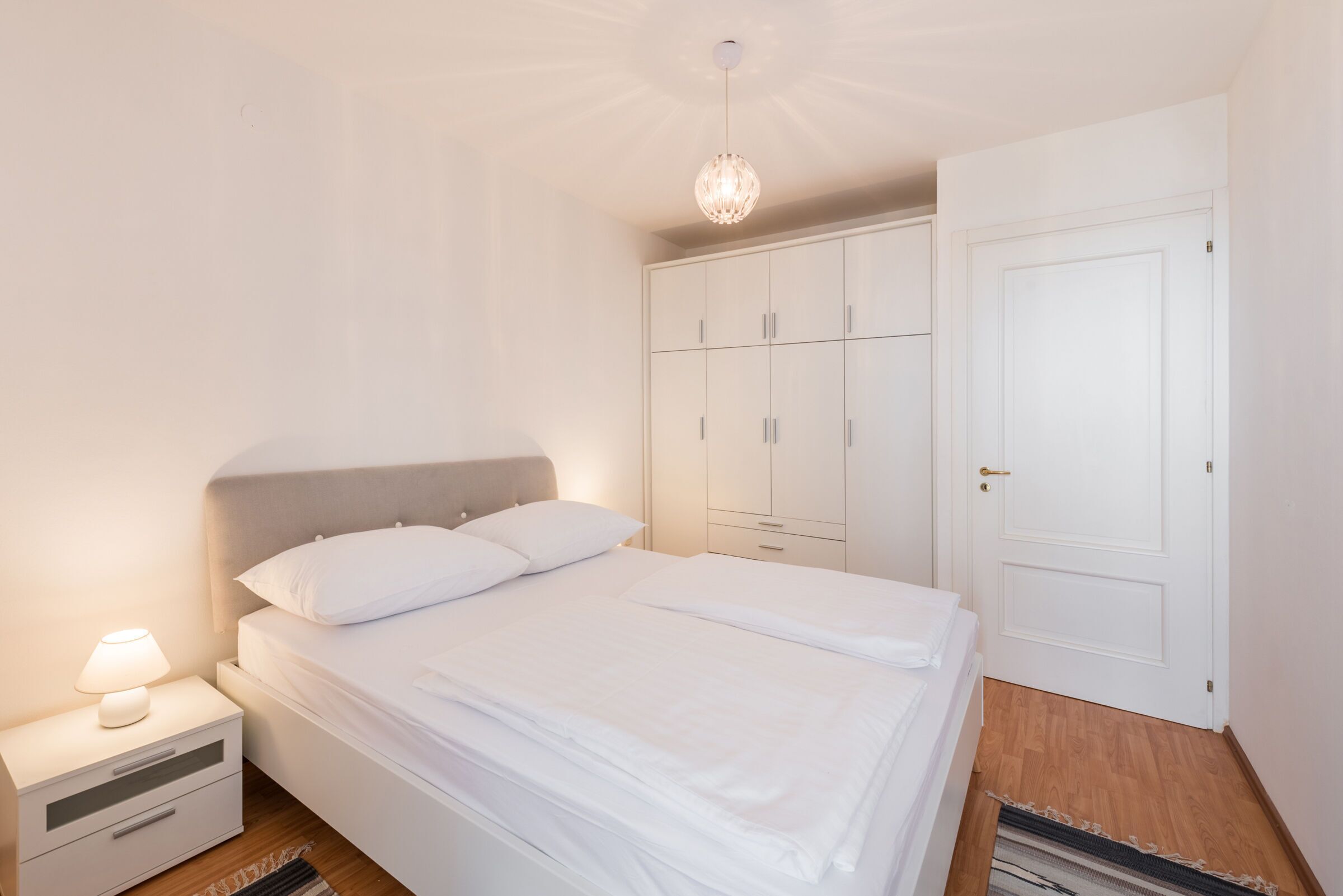 Ein Schlafzimmer mit Bett, Nachttisch, Kleiderschrank und einer Tür.