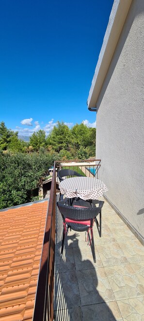 Enjoy a serene view of the lush landscape from this balcony with a table and chair.