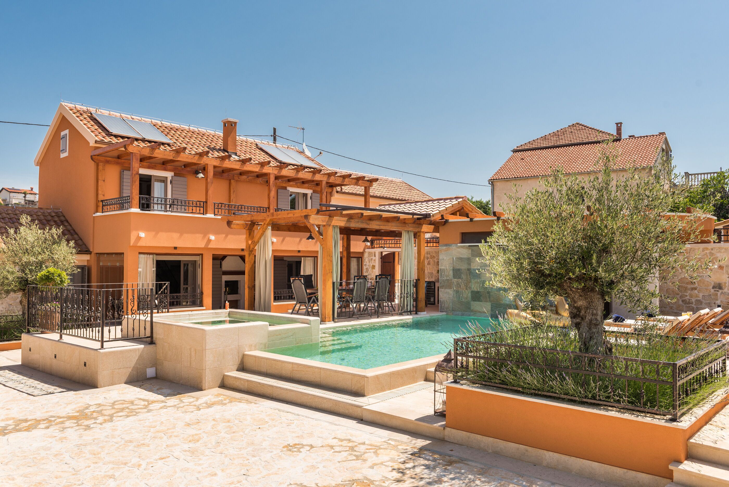 Een tweelaags huis met een zwembad, buitenmeubilair en een pergola.