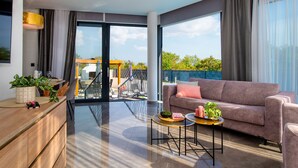 A modern living room with a sofa, a coffee table, and a dining area with a table and chairs. - Villa Laurel (Rupe)