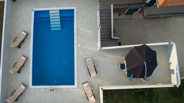 An aerial view of a swimming pool with lounge chairs and an umbrella. - Villa Natura (Muc)