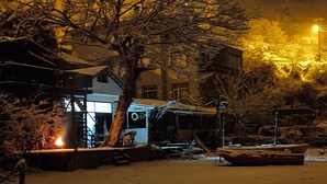 A snowy outdoor area with a tree, a building with a visible window, and a street lamp. - Çeşmeönü Bungalov  (Persembe)