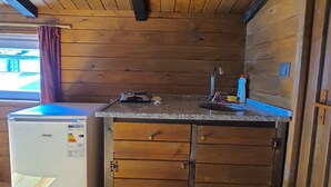 A compact kitchen with wooden cabinets, a built-in refrigerator, and a granite countertop. - Çeşmeönü Bungalov  (Persembe)