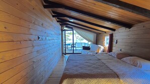 A wooden cabin interior with a bed, wooden walls, and a sloped ceiling. - Çeşmeönü Bungalov  (Persembe)