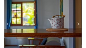 A teapot on a wooden table with a window in the background.