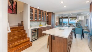 A modern kitchen with wooden cabinetry, a central island, and a view to the outside. - Simply Stunning Condo, C202 is one of of the best! (Lahaina)