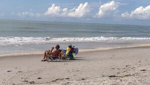 A beach with people relaxing on chairs, a clear sky, and the ocean in the background. - Blind Pass E103 - over 1500 sq ft ~ 8 person occupancy (Sanibel)