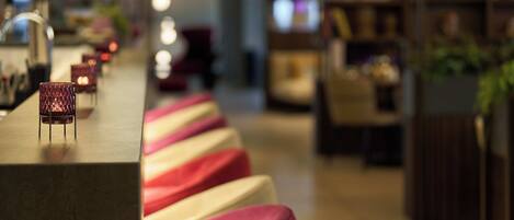 A bar area with a long counter and multiple cushioned seating areas in different colors.