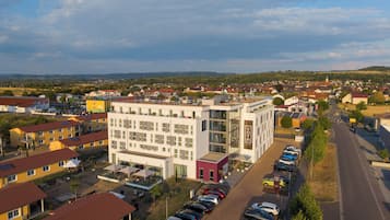A hotel with a modern design, featuring a rooftop terrace and a parking lot.