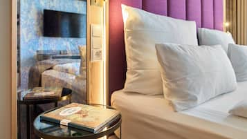 A hotel room with a bed, bedside table, and a view of the outside.
