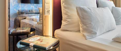 Habitación de hotel con cama, mesita de noche y vistas al exterior.