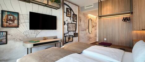 Une chambre d’hôtel moderne dotée d’un grand lit, d’un téléviseur à écran plat fixé au mur et d’une armoire en bois.