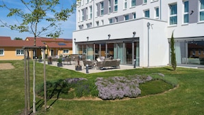 Un hotel moderno con un patio, mobiliario exterior y un jardín bien cuidado.