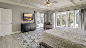 Een slaapkamer met een bed, een televisie, een stoel, een dressoir en uitzicht op de omgeving.