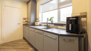 Une cuisine moderne équipée d’un four encastré, d’une machine à café et d’une fenêtre offrant une belle vue.