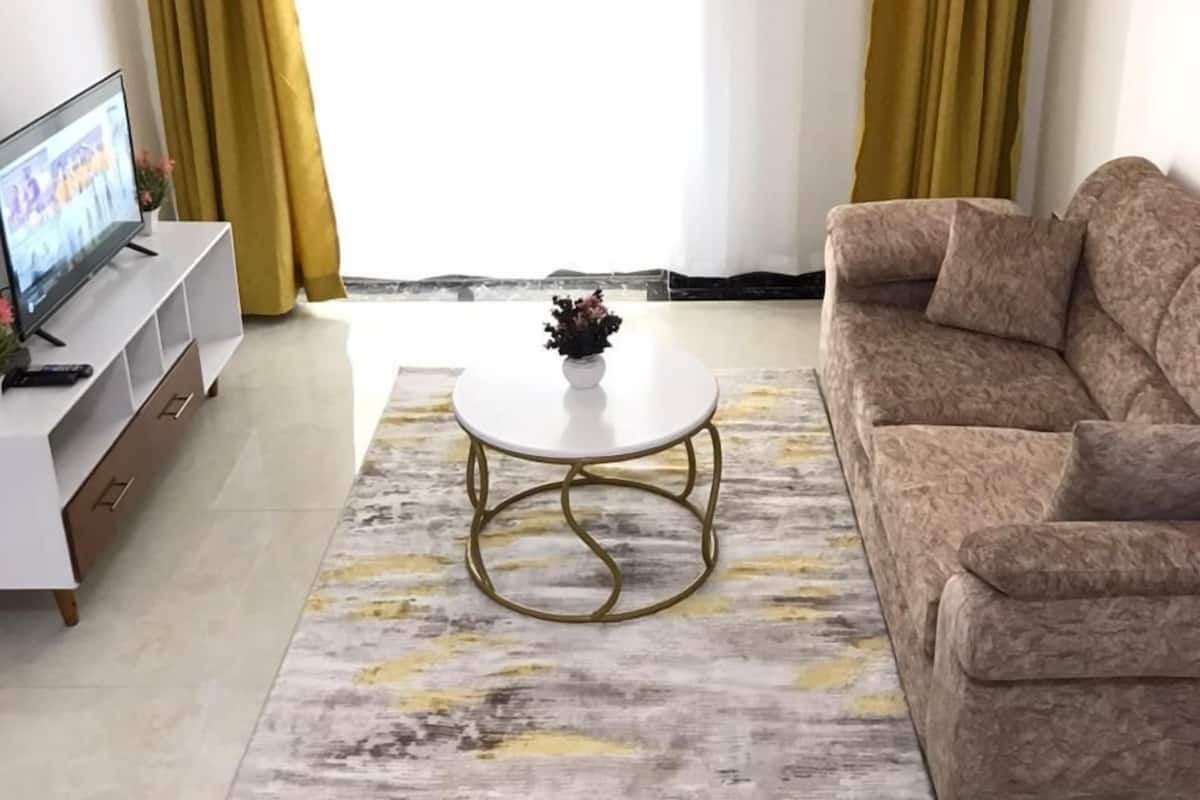 A living room with a sofa, a coffee table, a TV, and curtains.