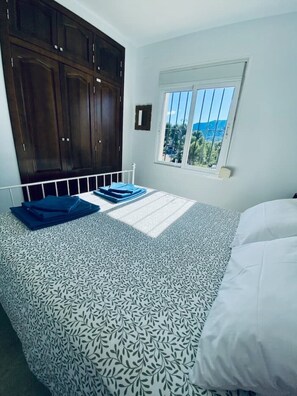 Ein Schlafzimmer mit einem Bett, einem Fenster mit Blick und dunklen Holzschränken.