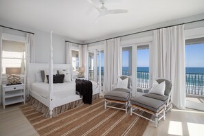 Quarto com cama de dossel, chaise longue e vista para o oceano.